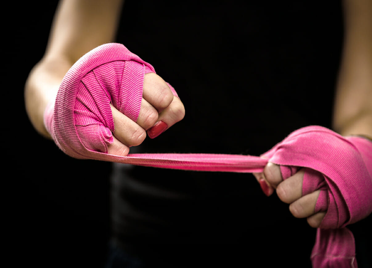 Woman is wrapping hands with pink boxing wraps