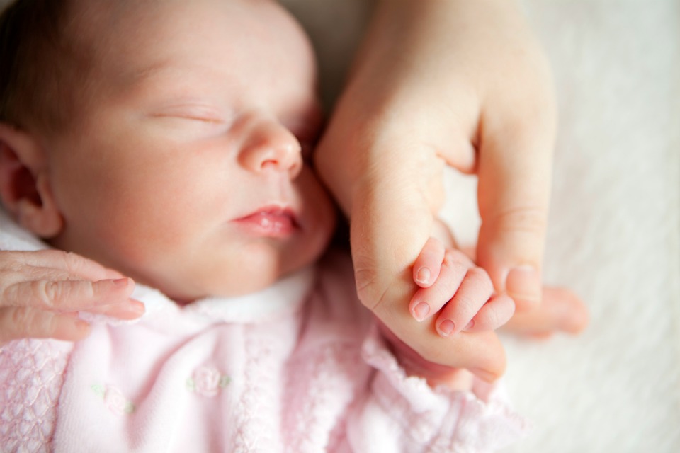 Newborn baby holding mother's hand.