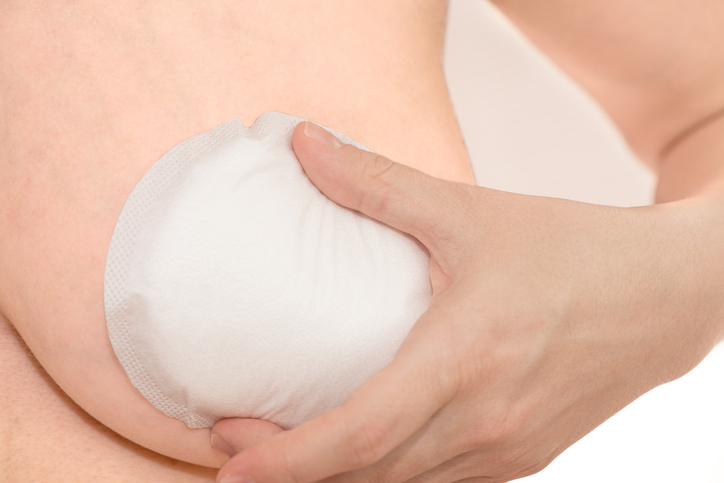 Woman putting absorbent pad to her breast to protect milk dripping