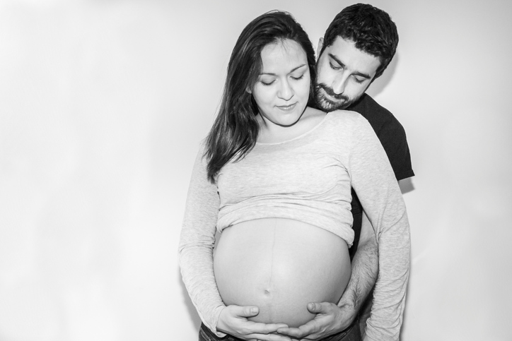 Pregnant woman posing with her husband. Black & White. Soft focus.