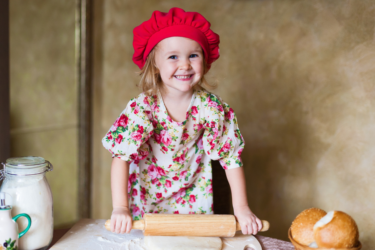 beautiful smiling little blonde girl in red beret with french bread