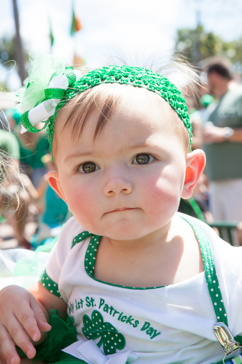 Delray Beach, United States - March 17, 2013: A little girl is dressed in green to watch St. Patrick's Day parade. She is wearing a tee shirt with "my first St. Patrick's Day" printed on it. The St. Patrick’s Day Parade is an annual event in Delray Beach that began in 1968 when an Irish local pub owner took a walk down Delray's main street with his Shillelagh and a green pig and declared it “my own parade.” Now Uniformed Emergency Service workers as well as commercial, civic, charitable, educational, and social groups participate. Groups throughout the United States and several foreign countries take part. Saint Patrick is the patron saint of Ireland. A good time is always had by adults and children alike at Delray’s parade in tribute to St. Patrick.