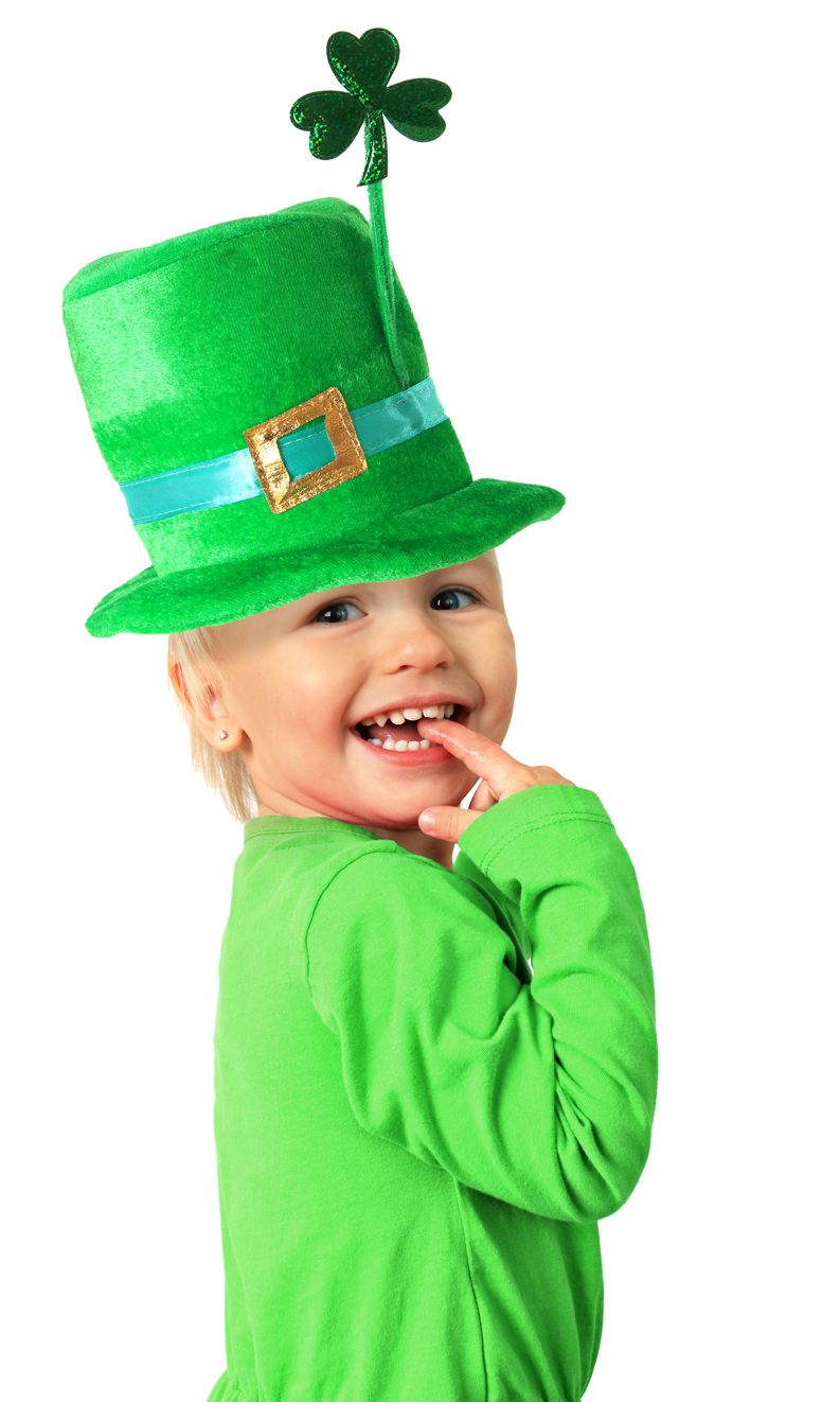 Happy smiling two year old girl wearing a St Patrick's day hat with a shamrock.