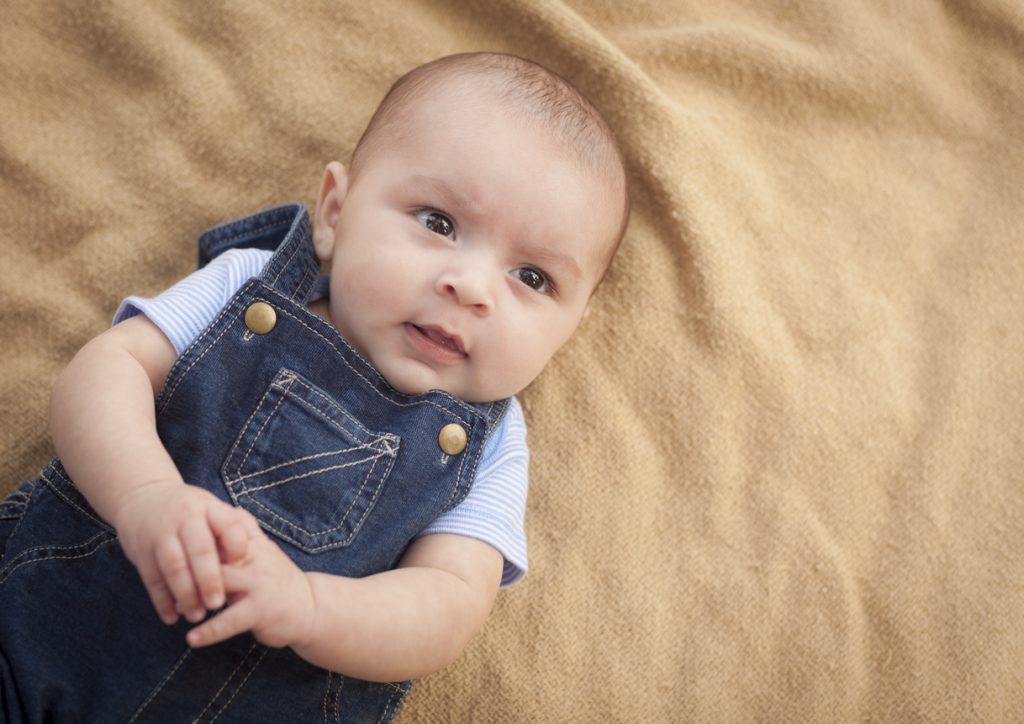 Happy Mixed Race Baby Boy Laying on Blanket.