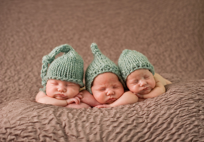 Newborn triplet girls sleeping with knit hats