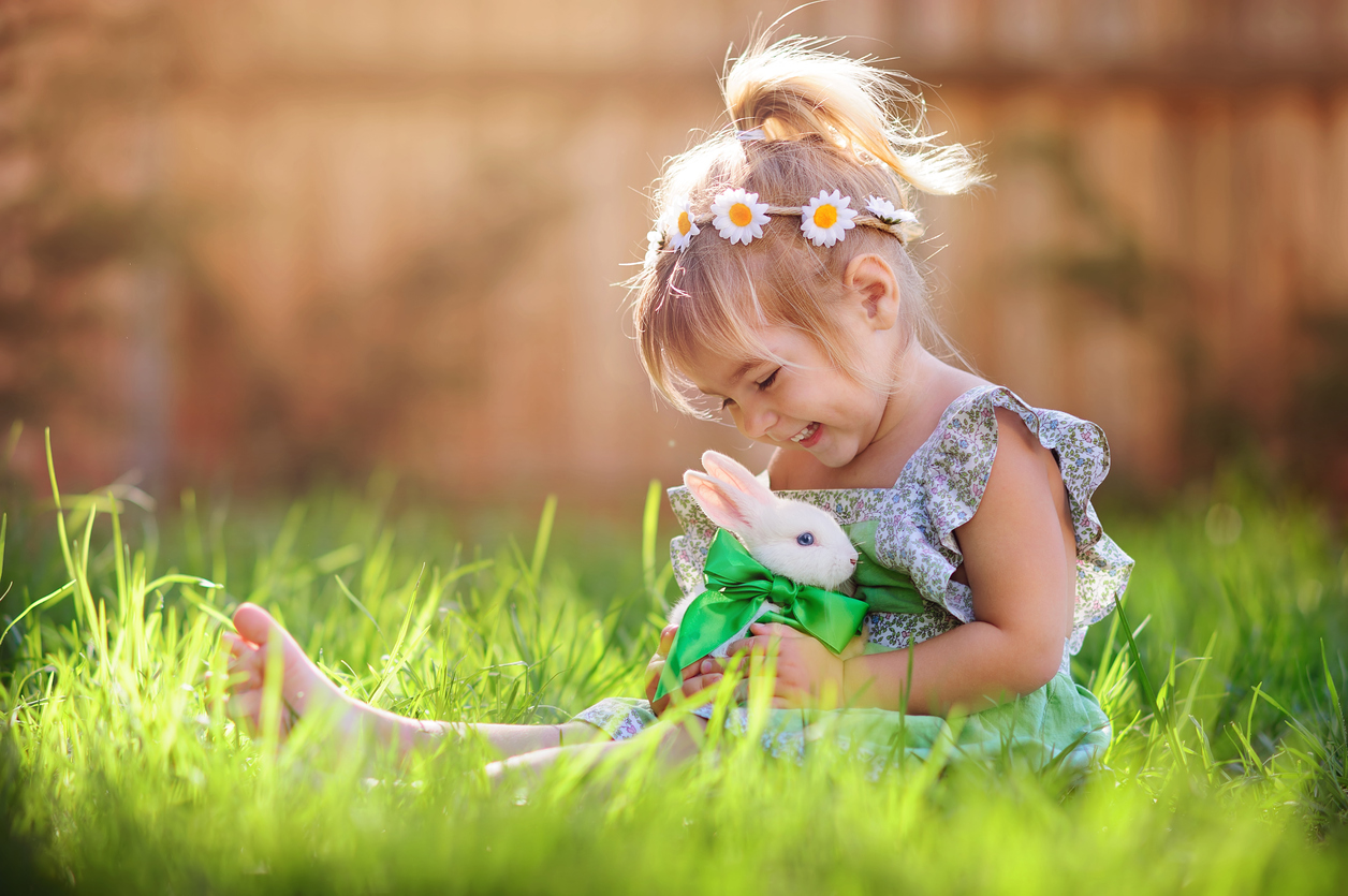 Cute little girl with a bunny rabbit has a easter at green grass background