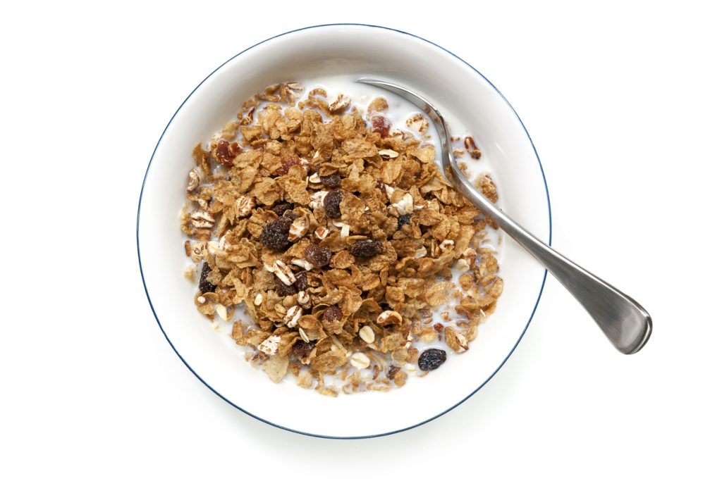 Bowl of cereal with spoon, isolated on white. Overhead view.