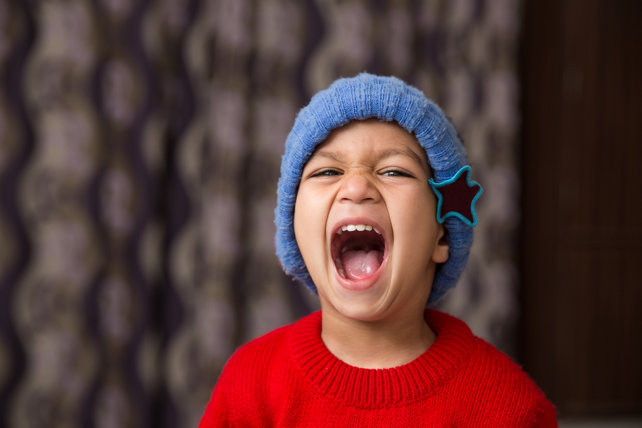 Cute Indian Kid striking a pose wearing red sweater and blue cap with a big laugh avaialble with clipping path