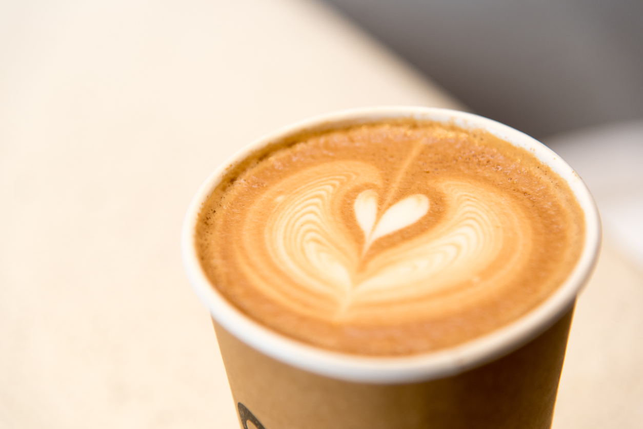 beautiful latte art arabica coffee in simple brown paper cup very good smell and delicious