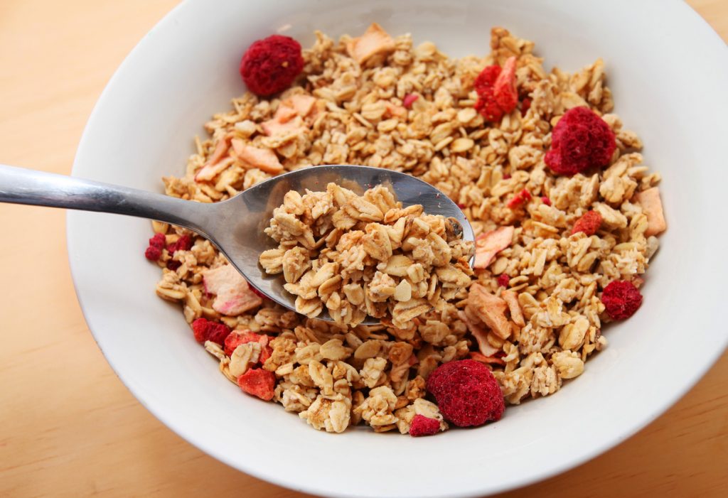 Oat Granola with dried raspberries breakfast cereal over wooden table background