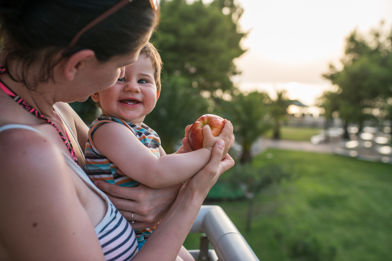 A boy keeping his apple safe from his mom