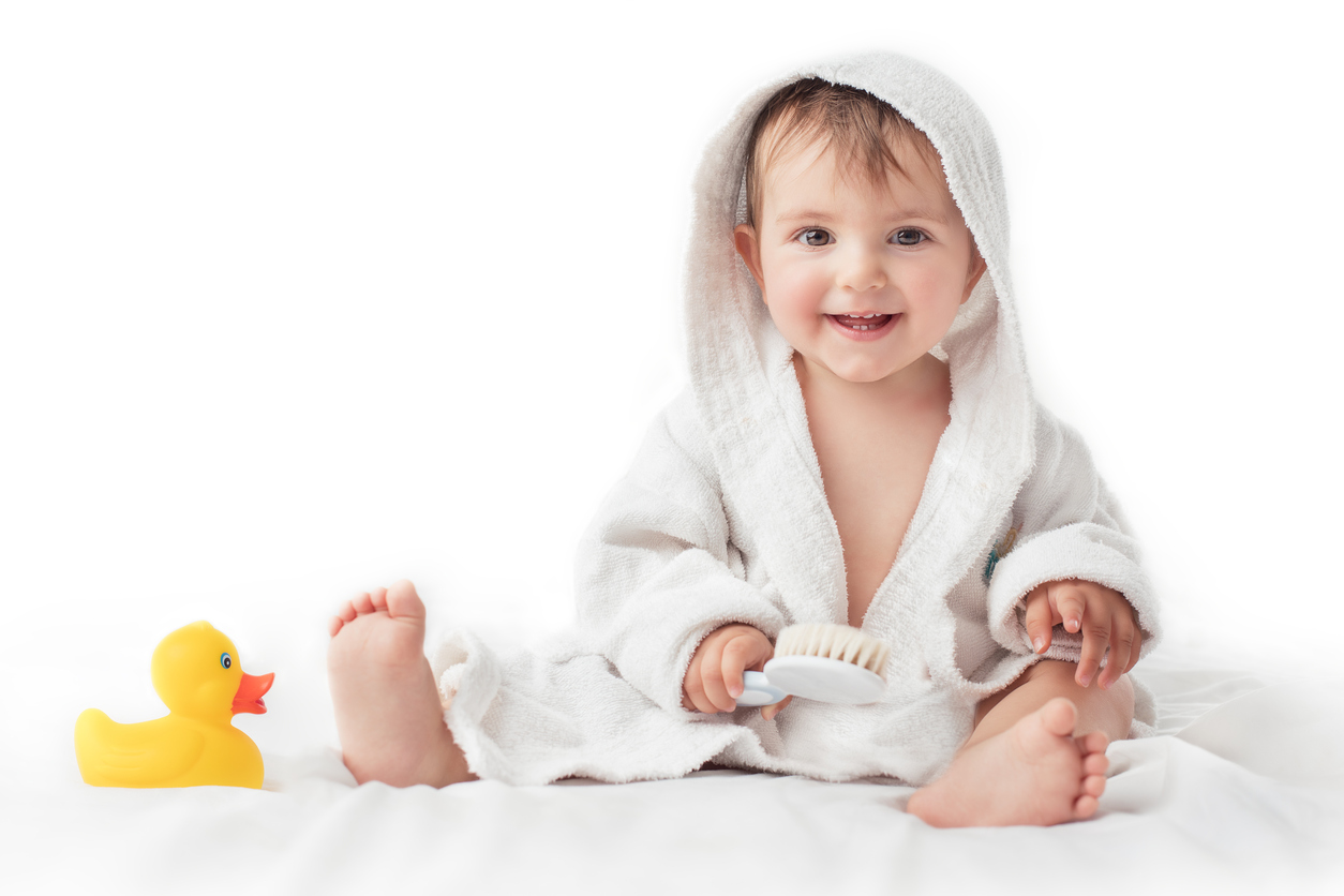 Little baby smiling under a white towel, bath time concept