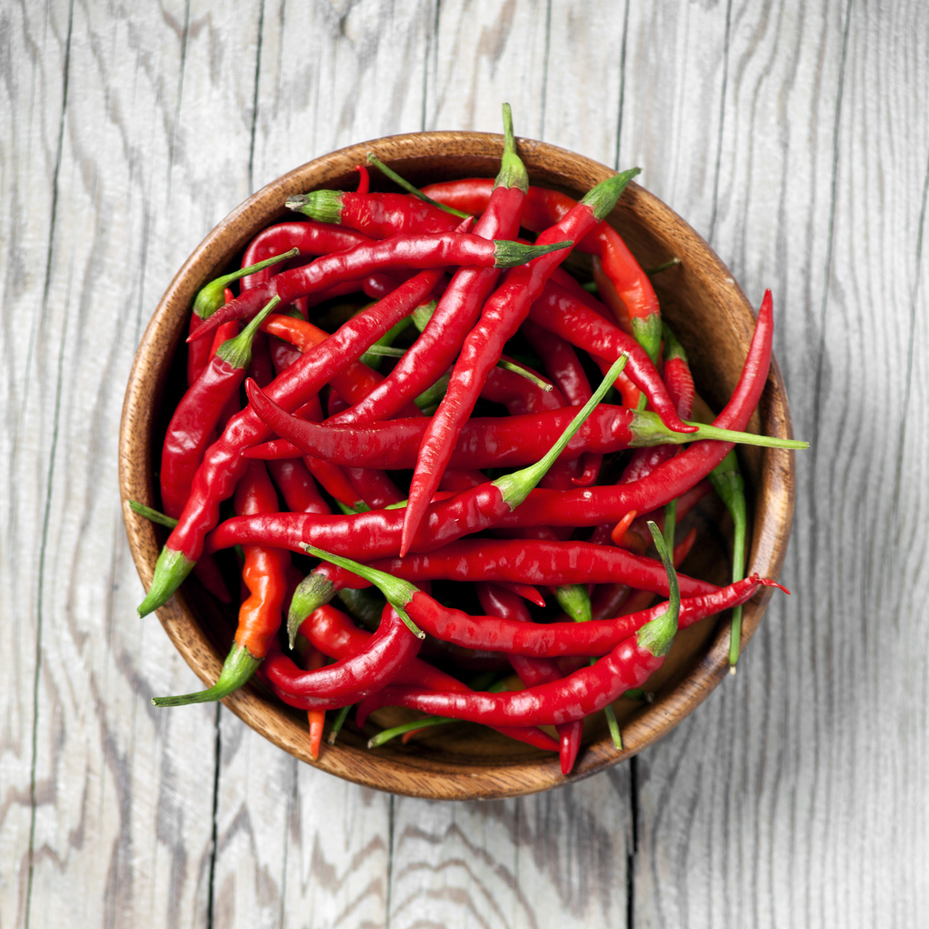 Red chili peppers in a bowl on wooden background