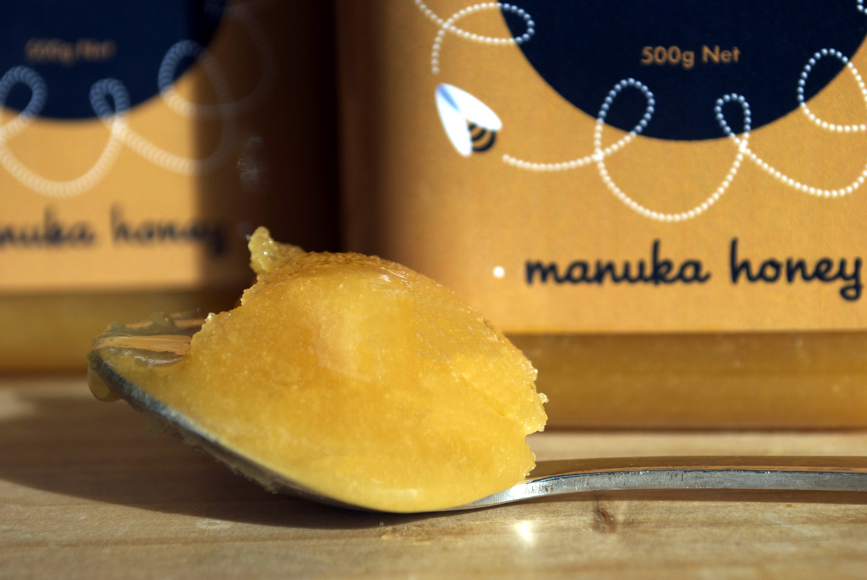 Motueka, New Zealand – August 15, 2014. Close-up of a spoonful of Manuka Honey. Out of focus are Manuka Honey jars, a product of the New Zealand company Moutere Beekeeping Ltd.