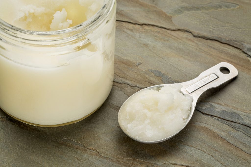 measuring tablespoon and glass jar coconut cooking oil on a slate rock background