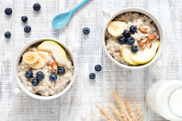 Oatmeal porridge in bowl on white table top view