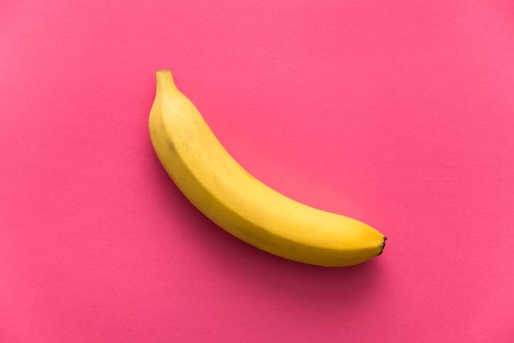 One yellow ripe banana on rose quartz background