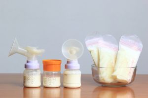 Bottles and frozen breast milk storage bags for new baby on wooden table