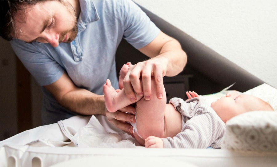 Young father changing nappy to his cute little baby son