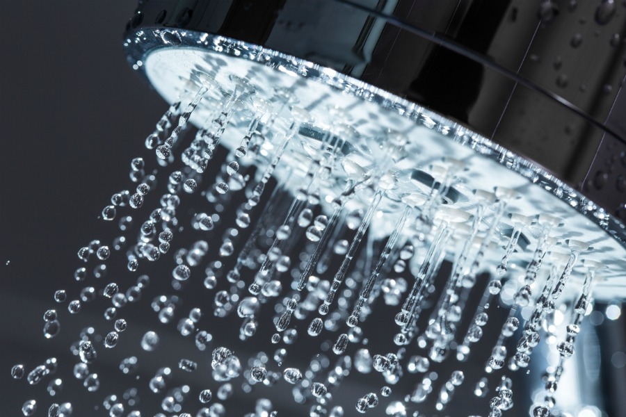 Shower Head with Water Stream on Black Background