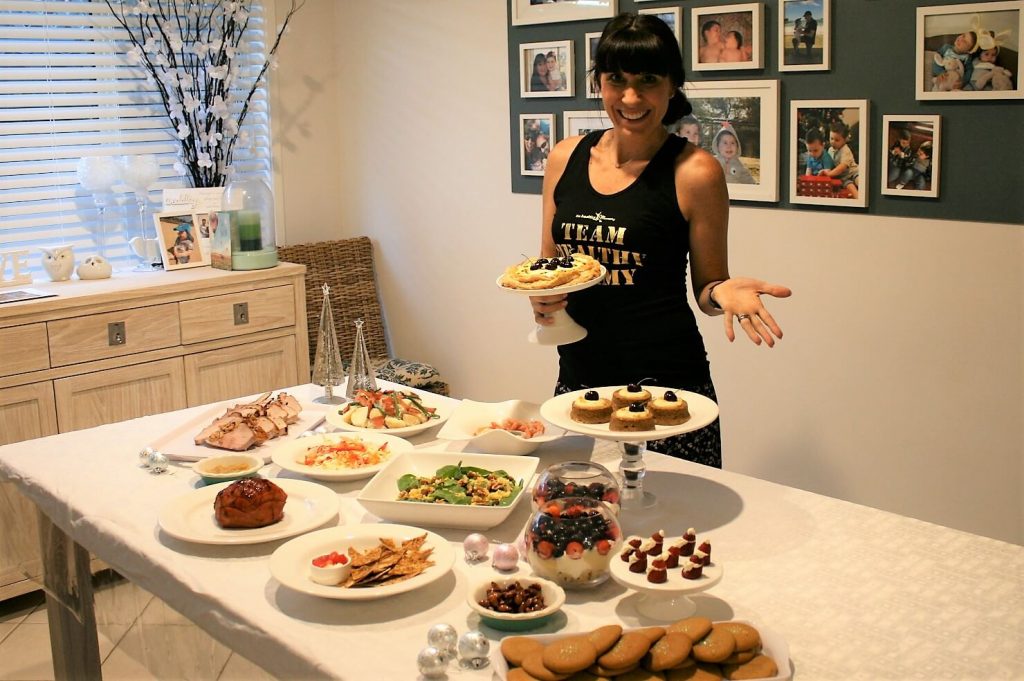 Mum behind table with Christmas meals and treats on it 