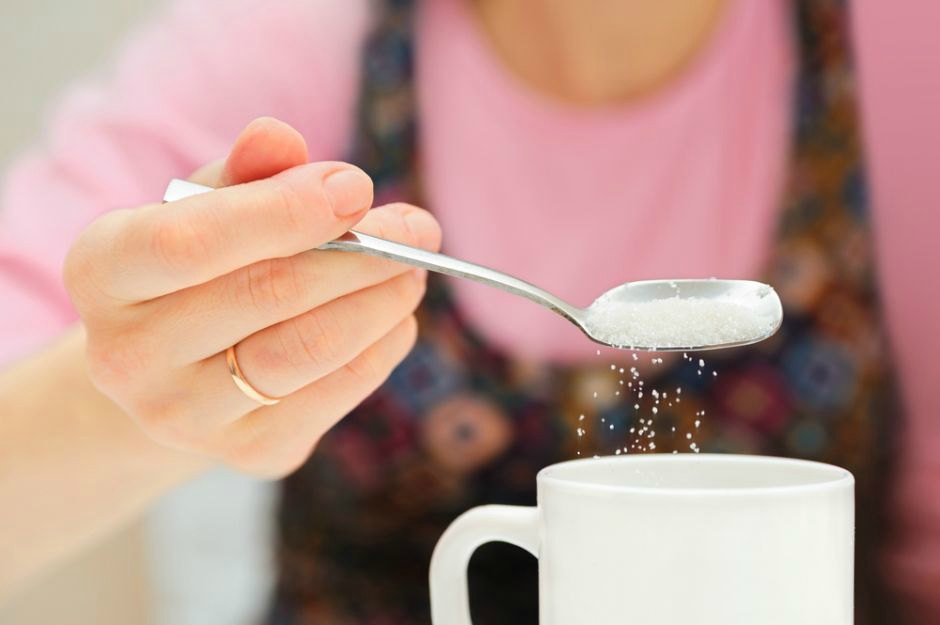 woman putting sugar in tea coffee