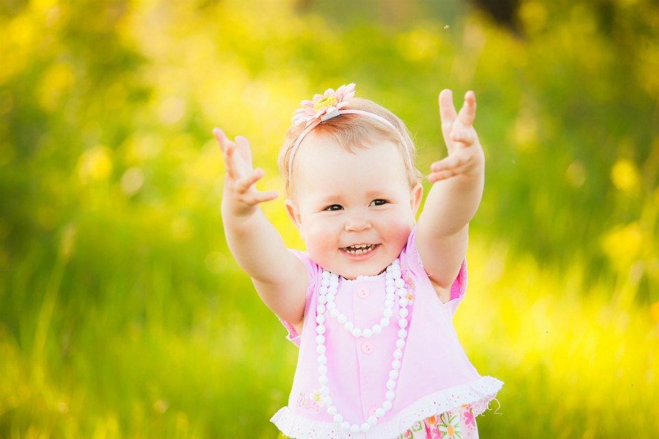 Happy daughter dressed in pink clothes playing at nature. Sunshine spring or summer day