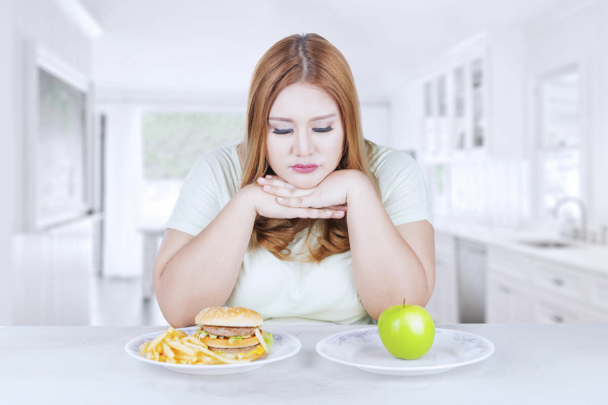 emotional eating Confused woman choose apple or hamburger