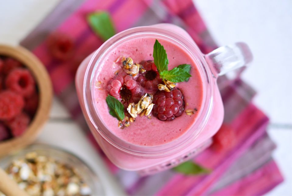 Berry smoothie in a glass jar on the breakfast with raspberries, oatmeal and honey on a white background,top view