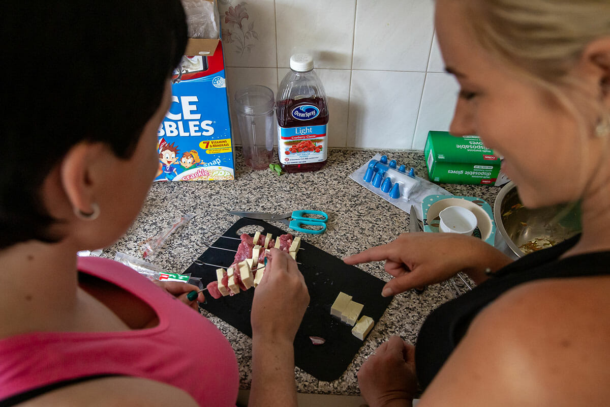 kaitie helping nicole make skewers preparing food