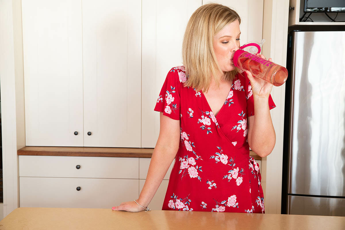 shanyn drinking from hydrate water bottle in kitchen