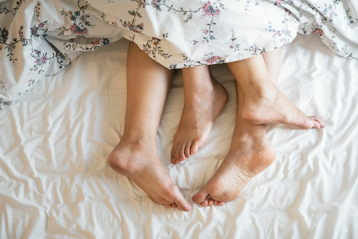 couples legs poking out of bedsheets Photo by rawpixel on Unsplash