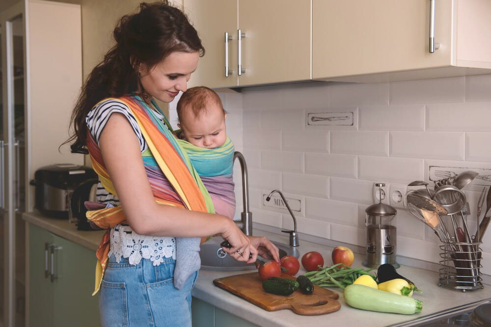 mother-in-kitchen-preparing-healthy-food-with-baby-in-carrier-or-sling-losing-weight-after-pregnancy