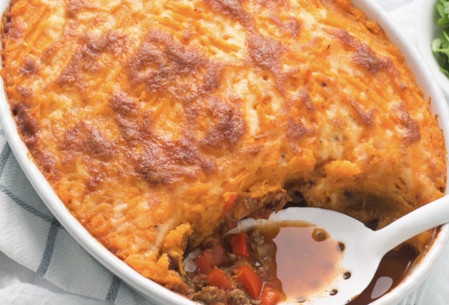 Image of the shepherds pie recipe cooked in a white casserole dish with white scoop in it